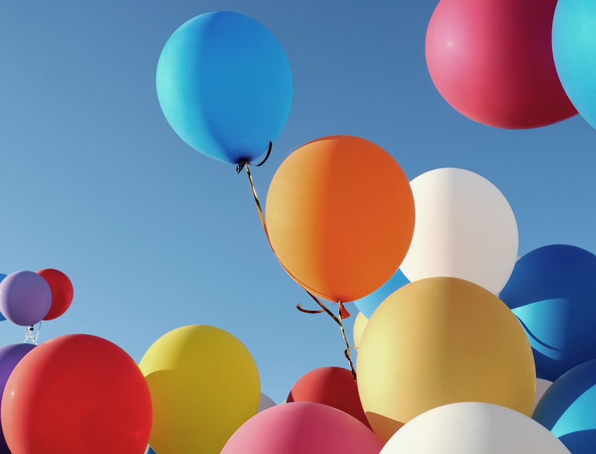 Bunte Luftballons schweben fröhlich am Himmel und verleihen der Szene eine festliche Atmosphäre.